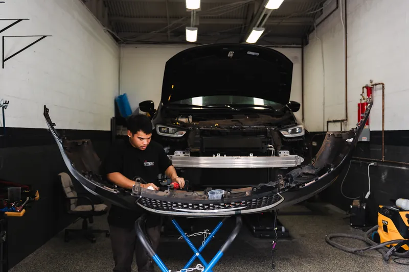 A technician rebuilding a vehicle's front end after a collision