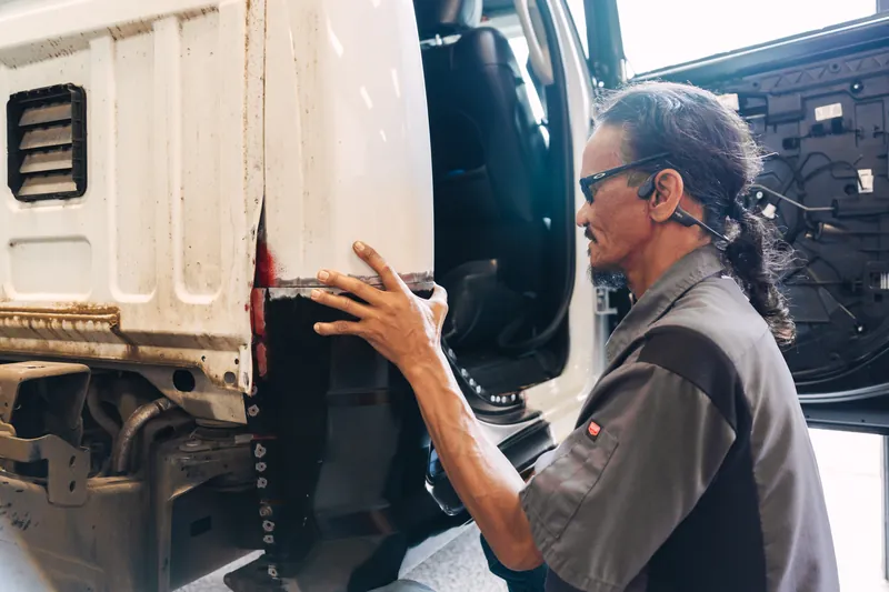 A technician fitting a replacement panel to a truck