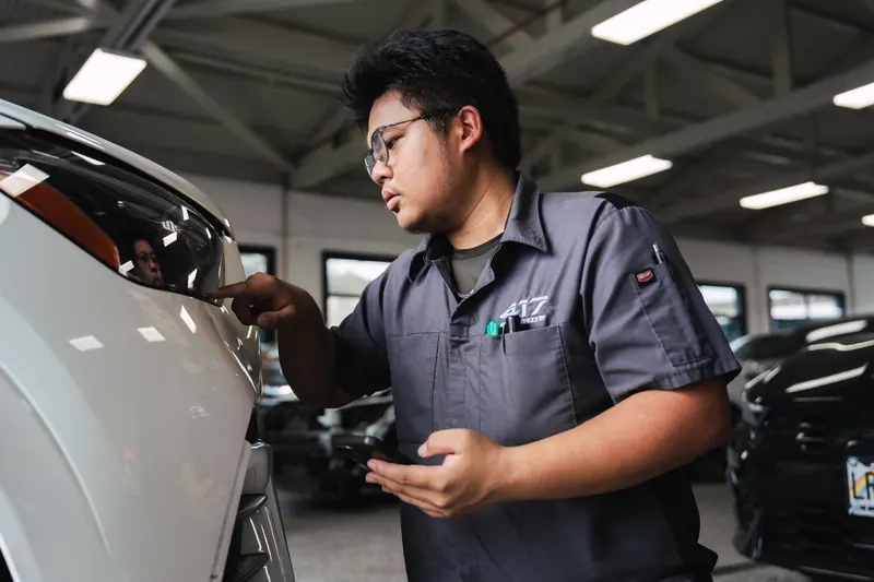 A technician working under the hood during a collision repair