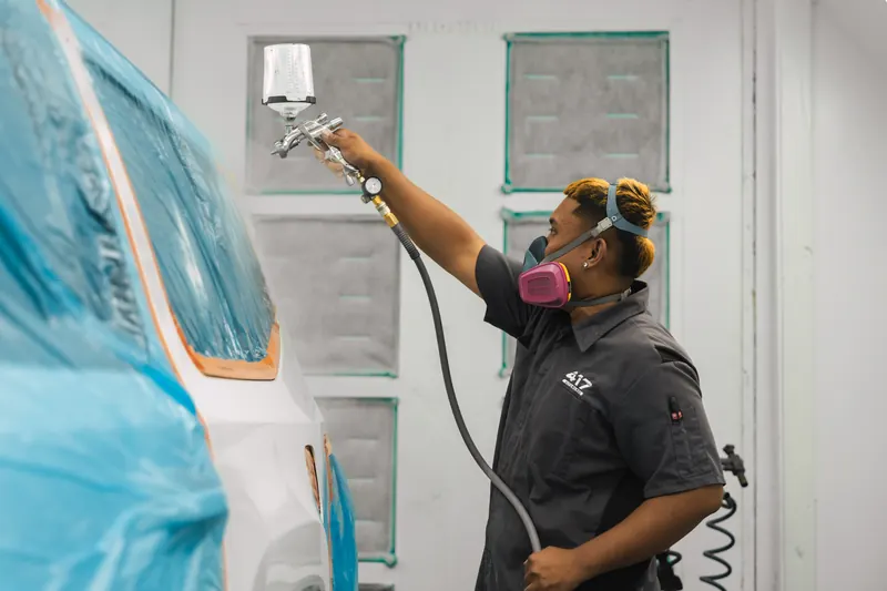 A technician spraying factory-matched paint in the booth