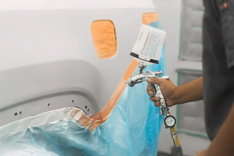 Spraying color onto a masked panel with a spray gun